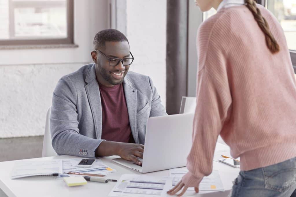 Male and female colleagues being at working place, check documentation as prepare business report on